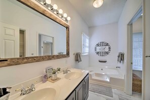 Une salle de bain avec deux lavabos, un grand miroir et une baignoire.