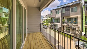 A balcony with a ceiling fan, wooden floor, and a view of neighboring apartment buildings. - Bright & Spacious Houston Townhome: Near Dtwn (Houston)