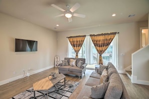 A living room with a sofa, a coffee table, and a TV mounted on the wall. - Bright & Spacious Houston Townhome: Near Dtwn (Houston)