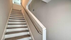 A staircase with wooden steps and white handrails, leading to a landing with a small window. - Bright & Spacious Houston Townhome: Near Dtwn (Houston)