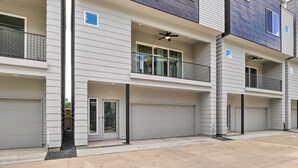 A multi-story residential building with a garage on the ground floor, balconies on the upper floors, and a concrete driveway. - Bright & Spacious Houston Townhome: Near Dtwn (Houston)
