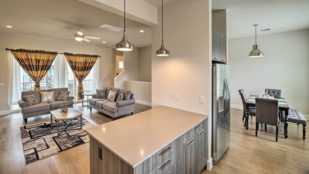 A spacious living area with a large island, a dining table, and a kitchen area with a refrigerator. - Bright & Spacious Houston Townhome: Near Dtwn (Houston)