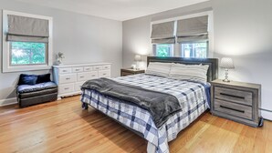 Een slaapkamer met een bed, nachtkastjes, een dressoir en een bankje.
