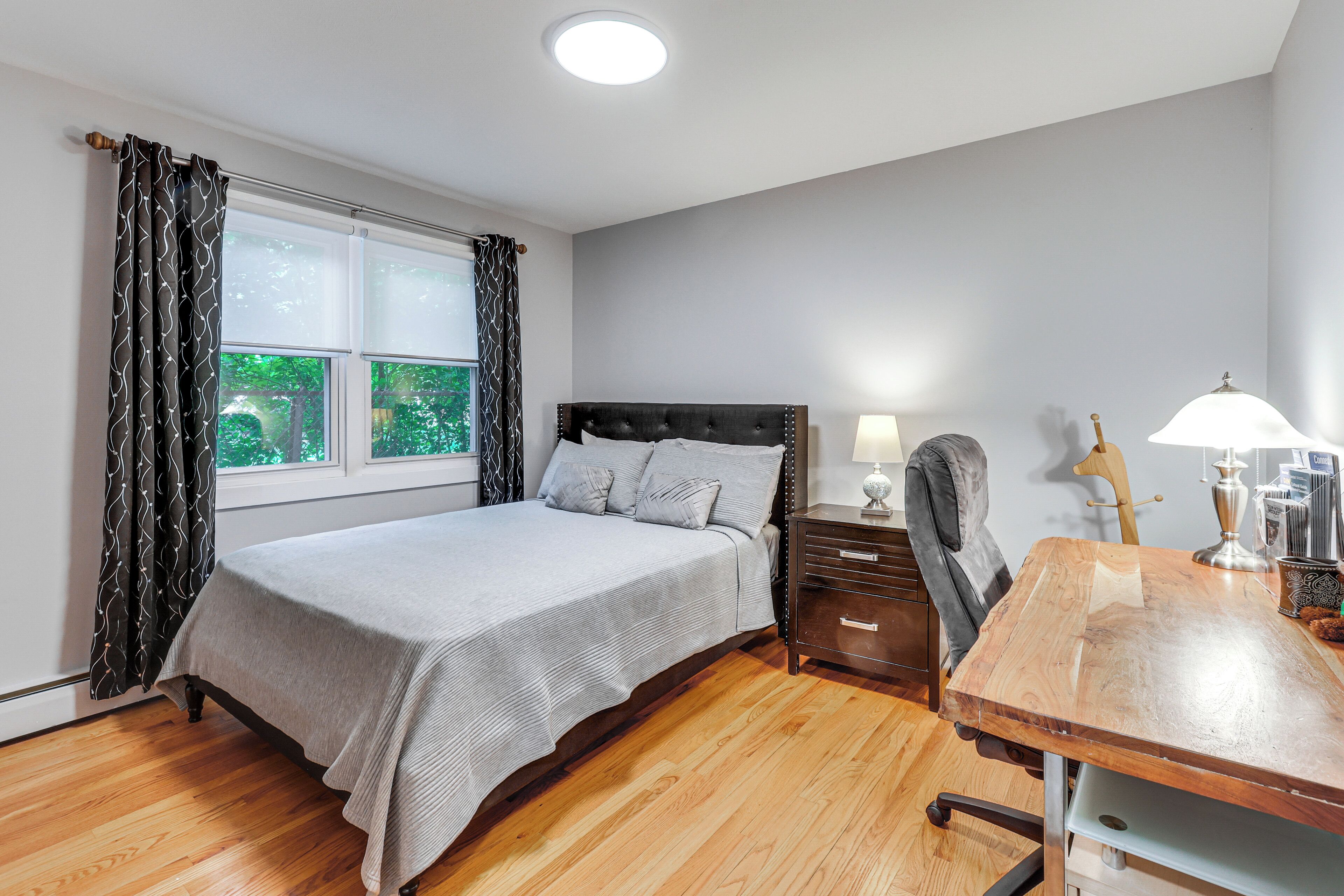 A bedroom with a bed, a nightstand, a desk, and a chair.