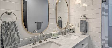 A bathroom with two sinks, a large mirror, and a towel rack.
