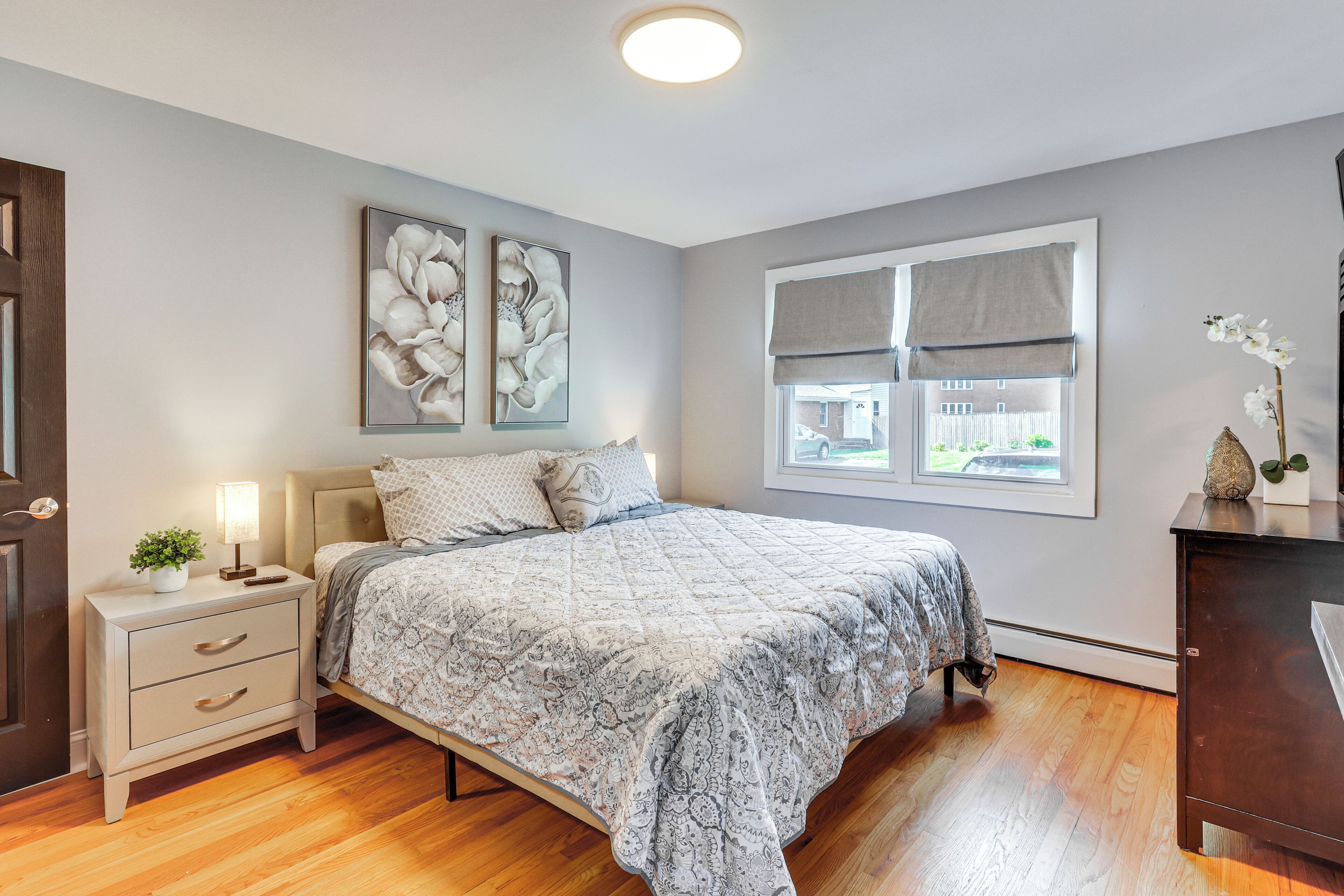 A bedroom with a bed, nightstand, and artwork on the wall.