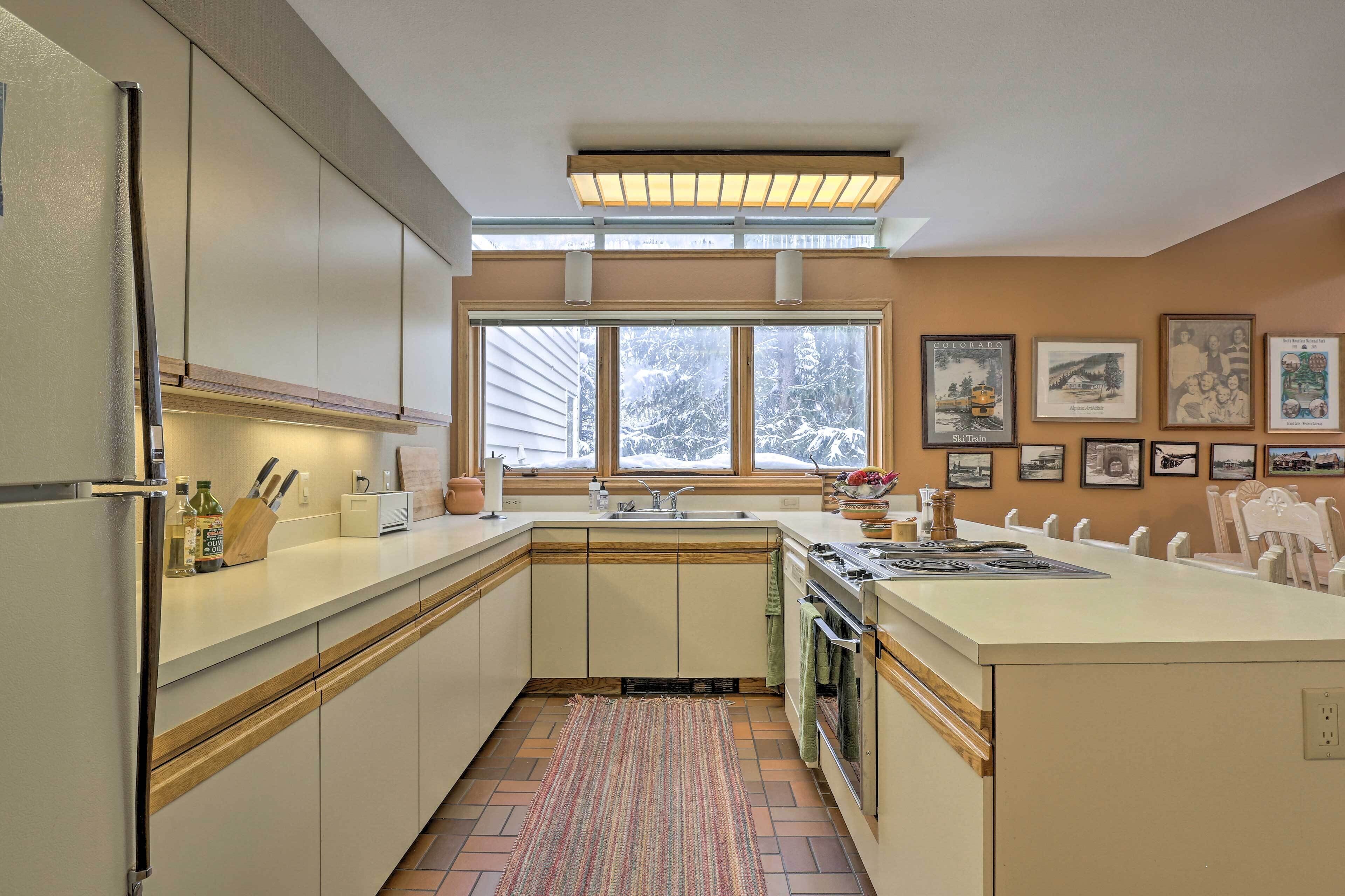 A kitchen with a central island, a window with a view of trees, and framed pictures on the wall.