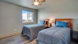 A bedroom with two beds, a ceiling fan, a window with a view, and a nightstand with a lamp. - Saratoga Retreat ~ 3 Mi to Saratoga Lake! (Saratoga)