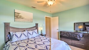 Een slaapkamer met een bed, een nachtkastje, een dressoir en een plafondventilator.