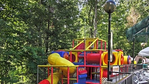 A playground with slides and climbing structures surrounded by a fence. - Unique Gatlinburg Cabin: Decks, Hot Tub, Fire Pit (Gatlinburg)