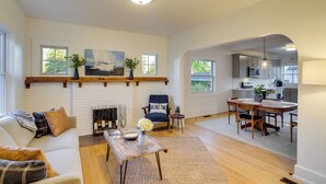 A living room with a fireplace, a dining area, and a kitchen visible through an archway. - Indiana Vacation Rental - Walk to Syracuse Lake! (Syracuse)