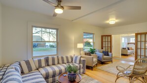 A modern living room with a sectional sofa, a small table with a plant, and a wicker chair. - Indiana Vacation Rental - Walk to Syracuse Lake! (Syracuse)