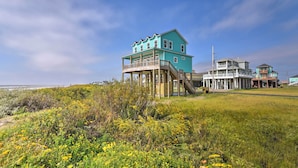 A coastal house with a wooden deck and a balcony, overlooking the beach. - Crystal Tides - Stunning Home W/oceanfront Views (Port Bolivar)