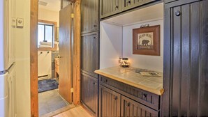 A kitchen with wooden cabinets, a countertop, and a framed picture of a bear. - Fireplace, Deck & Mtn Views: Grand Lake Home! (Grand Lake)