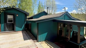 A small, single-story building with a dark green exterior, a front door, and a small porch area. - Fireplace, Deck & Mtn Views: Grand Lake Home! (Grand Lake)