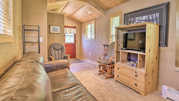 A cozy living room with a leather couch, wooden entertainment unit, and a television. - Fireplace, Deck & Mtn Views: Grand Lake Home! (Grand Lake)