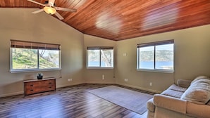 A spacious room with wooden flooring, a ceiling fan, and large windows offering a view of a natural landscape. - Waterfront Clearlake Retreat w/ Dock & Kayaks (Clearlake)