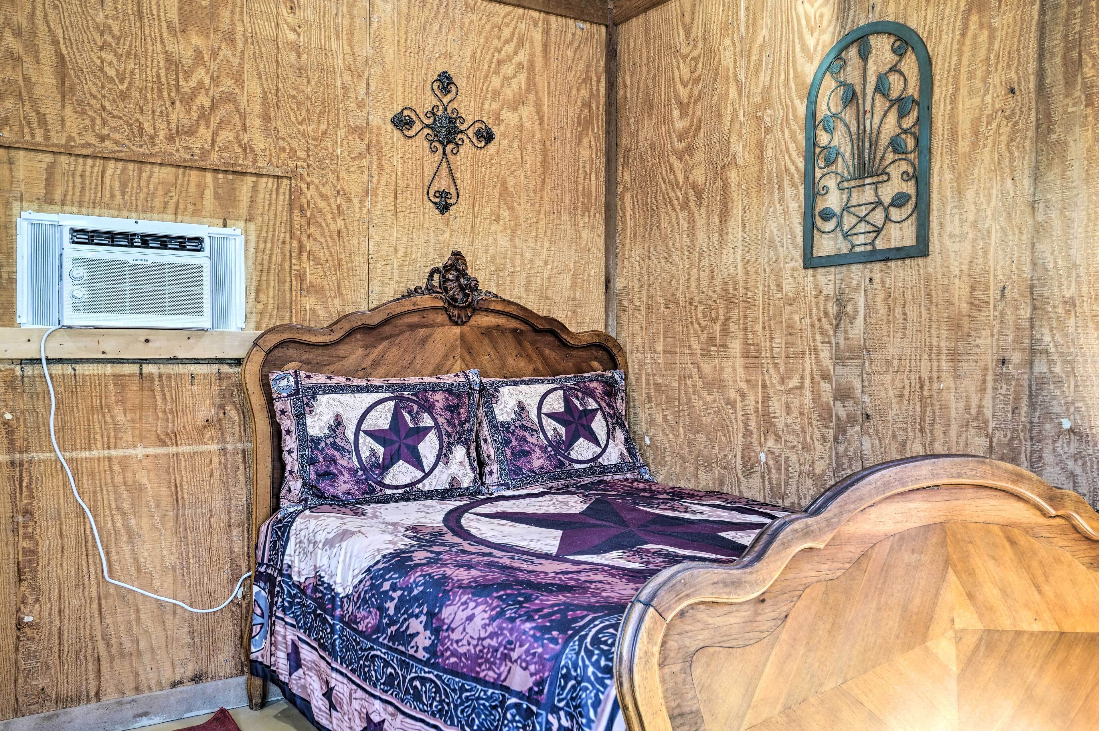 A wooden-paneled room with a bed, a wall-mounted air conditioner, and a decorative wall piece.