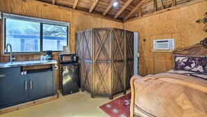 A wooden interior with a bed, a kitchen area, and a large window. - Waterfront Lake Dunlap Studio Cabin w/ Dock (New Braunfels)
