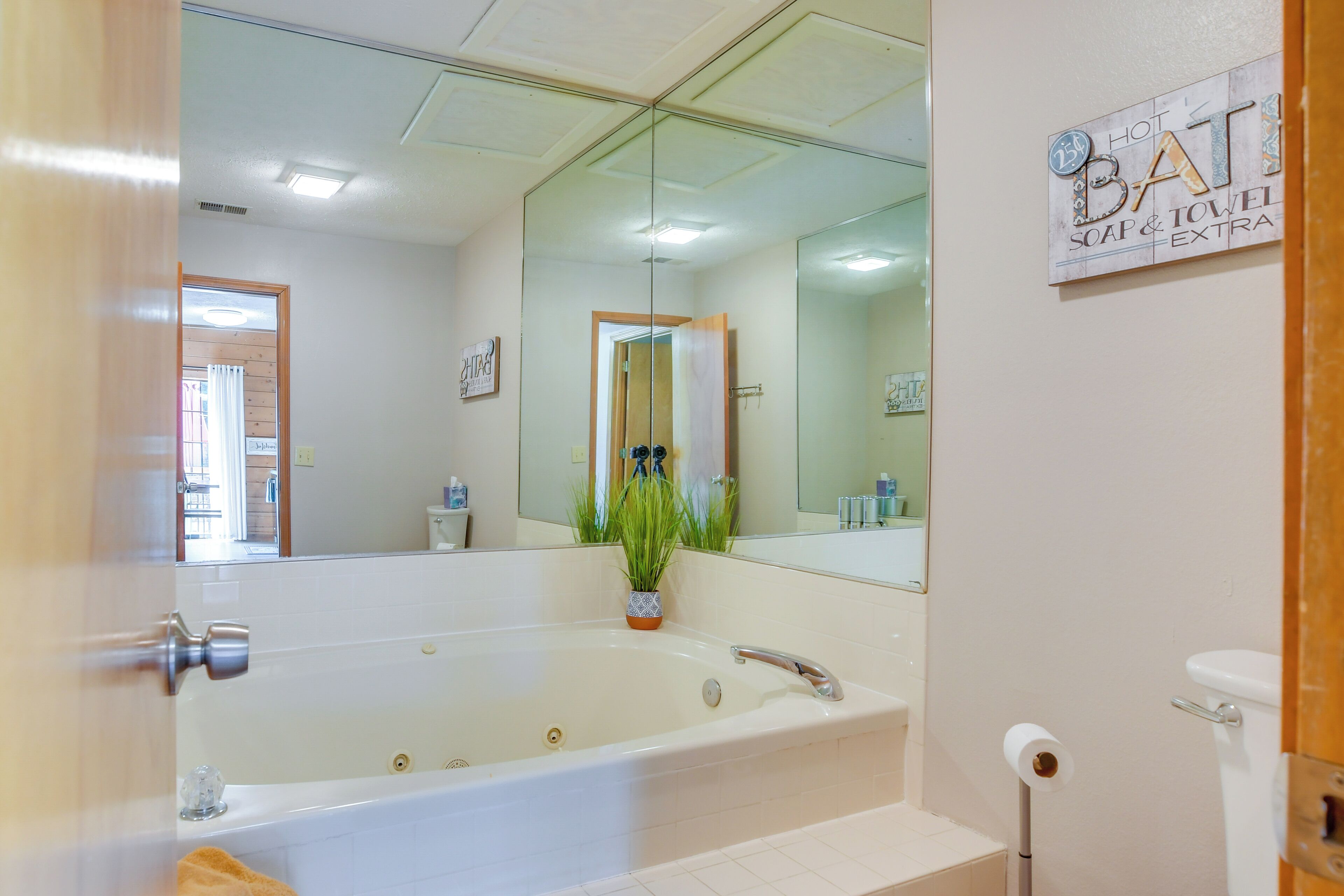 Une salle de bain équipée d’une grande baignoire, de toilettes, d’un miroir et d’un panneau indiquant la disponibilité de serviettes, de savon et d’autres articles de toilette supplémentaires.