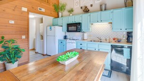A kitchen with light blue cabinets, a wooden table with a plant centerpiece, a microwave, stove, and dishwasher. - 3 Mi to Branson Strip! Townhome w/ Deck & Porch (Branson)