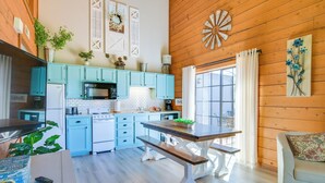A modern kitchen with light blue cabinets, a wooden dining table, and a white sofa. - 3 Mi to Branson Strip! Townhome w/ Deck & Porch (Branson)