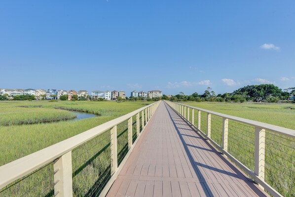 A wooden boardwalk leading to a residential area with houses and a small water body. - Beach & Pool Access: Hilton Head Resort Condo (Hilton Head Island)