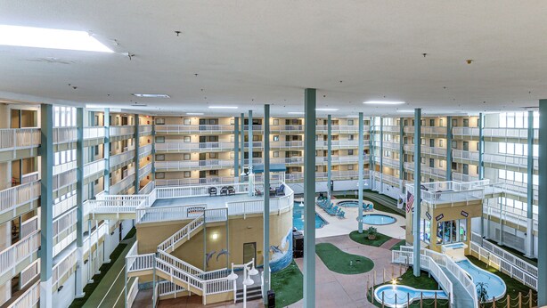A multi-level hotel atrium with balconies, a central courtyard, and a swimming pool. - Beach & Pool Access: Hilton Head Resort Condo (Hilton Head Island)