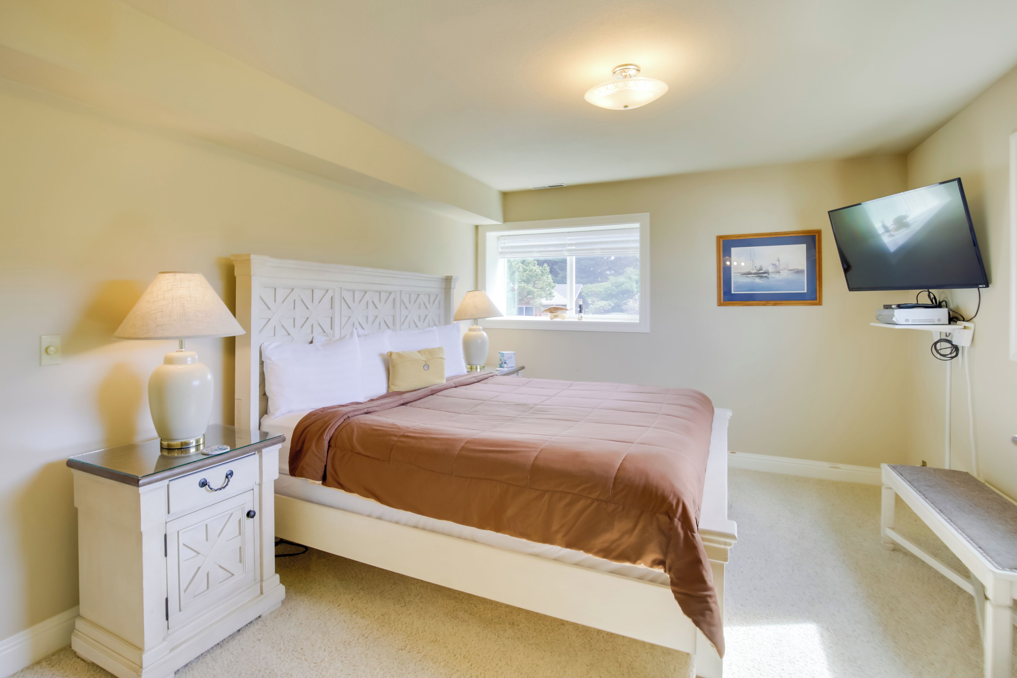 A bedroom with a bed, bedside tables, a TV, and a window.