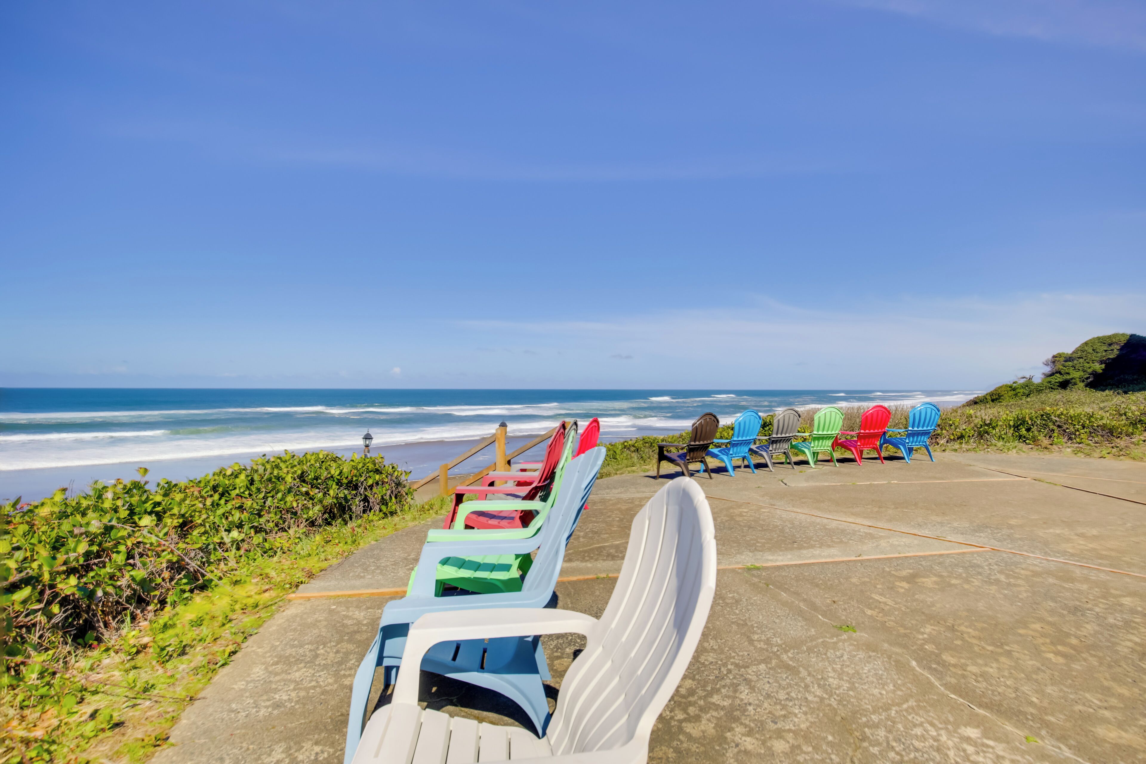 A beachside seating area with colorful Adirondack chairs facing the ocean.