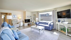 A modern living room with a sofa, coffee table, TV, and a fireplace. - Oceanfront Oregon Retreat - Pool, Sauna & Patio! (Lincoln City)