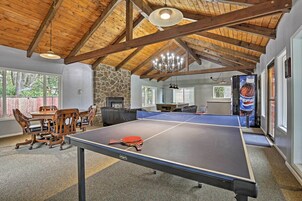 A ping pong table in a room with a stone wall, wooden ceiling beams, and a chandelier.