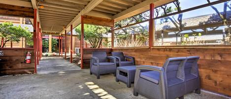 A covered outdoor seating area with wicker furniture and a fire extinguisher.