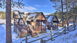 Reihle Holzhütten mit Veranden, umgeben von Schnee und Kiefern.