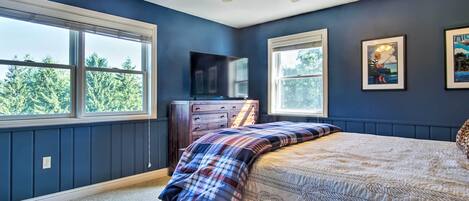 Une chambre à coucher avec un lit, une commode, un ventilateur de plafond et un téléviseur.