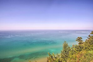 Eine Küstenlandschaft mit klarem Wasser, einem Sandstrand und üppiger Vegetation im Vordergrund.