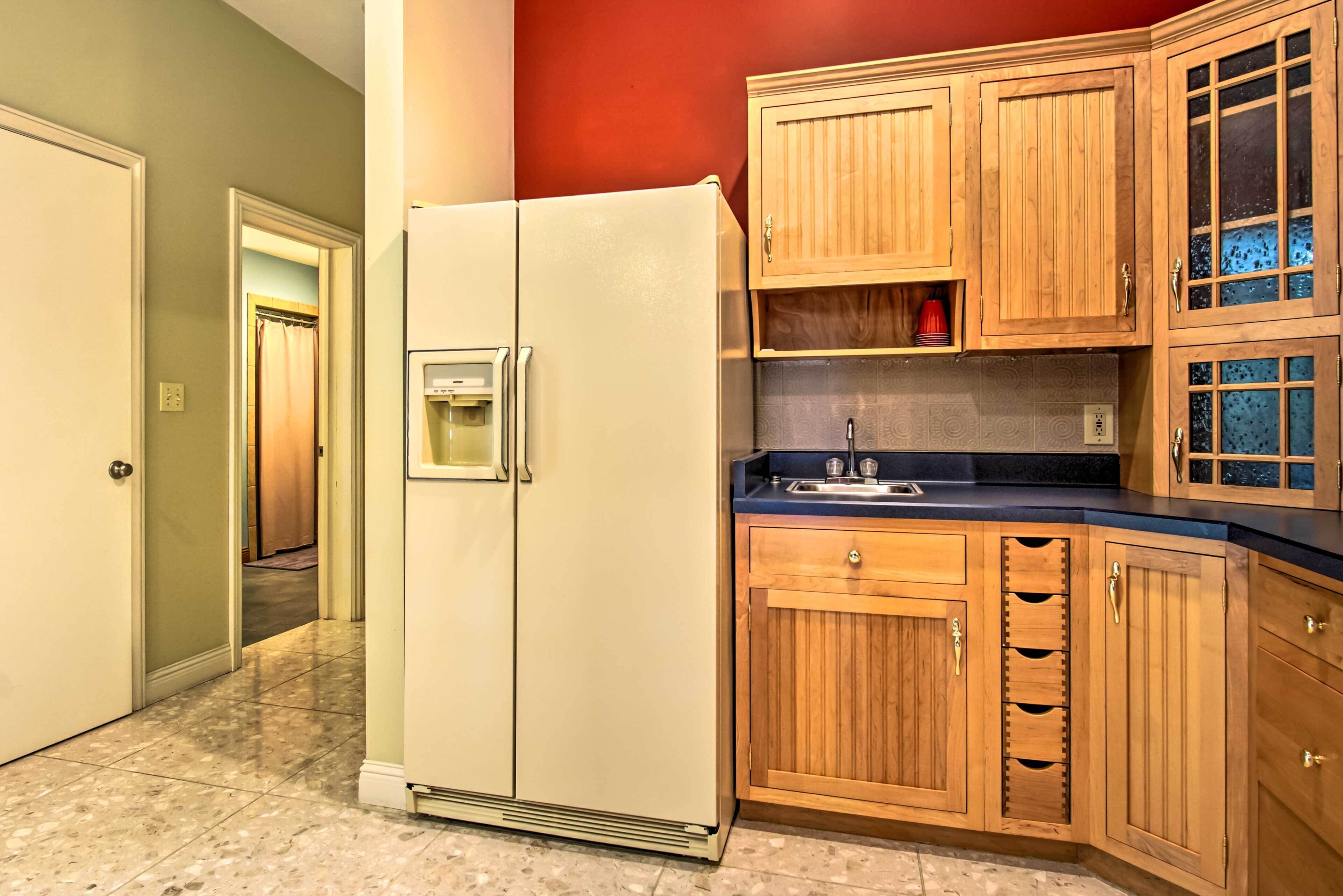 A kitchen with wooden cabinets, a white refrigerator, and a tiled floor.