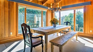 A wooden-paneled room with a large window, a wooden table, a bench, and a chandelier. - Hot Tub & Sauna! 7-acre Coastal Michigan Home (Ludington)