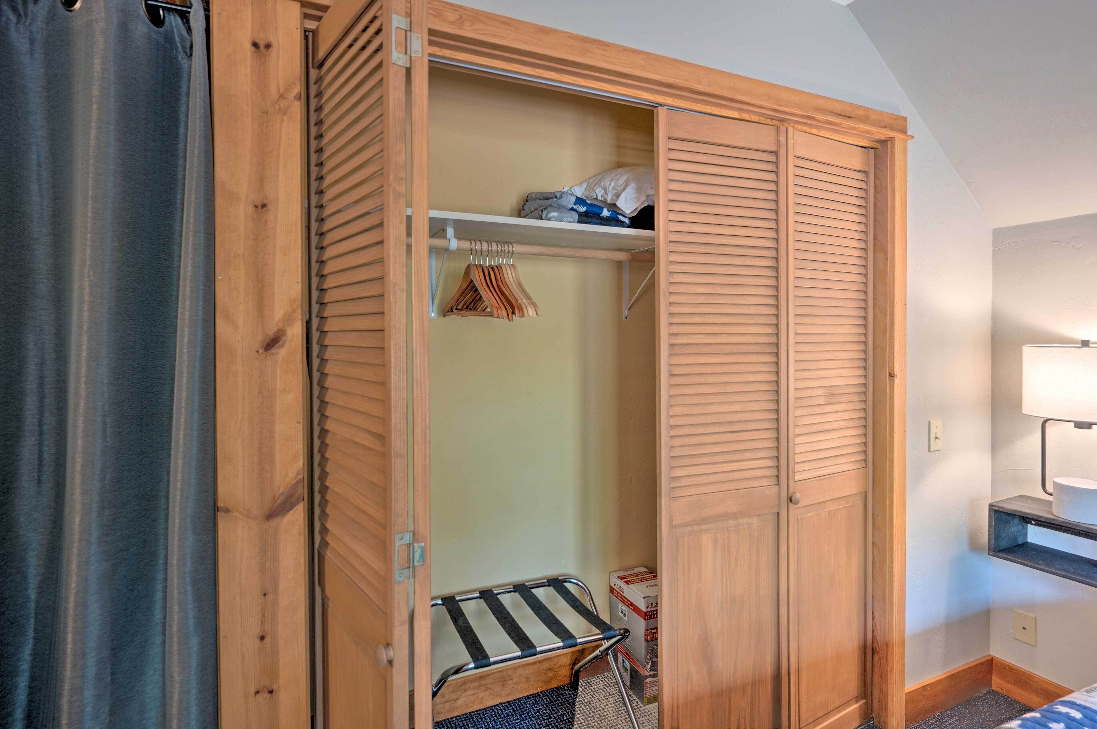 Ein begehbarer Kleiderschrank mit Holztüren, einer Kleiderstange und einem kleinen Regal.