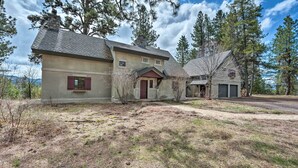 A two-story house with a stone chimney, a red door, and a garage. - Private Mccall Apartment w/ Mountain View! (McCall)