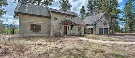 A two-story house with a stone chimney, a red door, and a garage.
