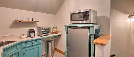 A compact kitchen with teal cabinetry, a stainless steel refrigerator, a microwave, a toaster, and a sink.