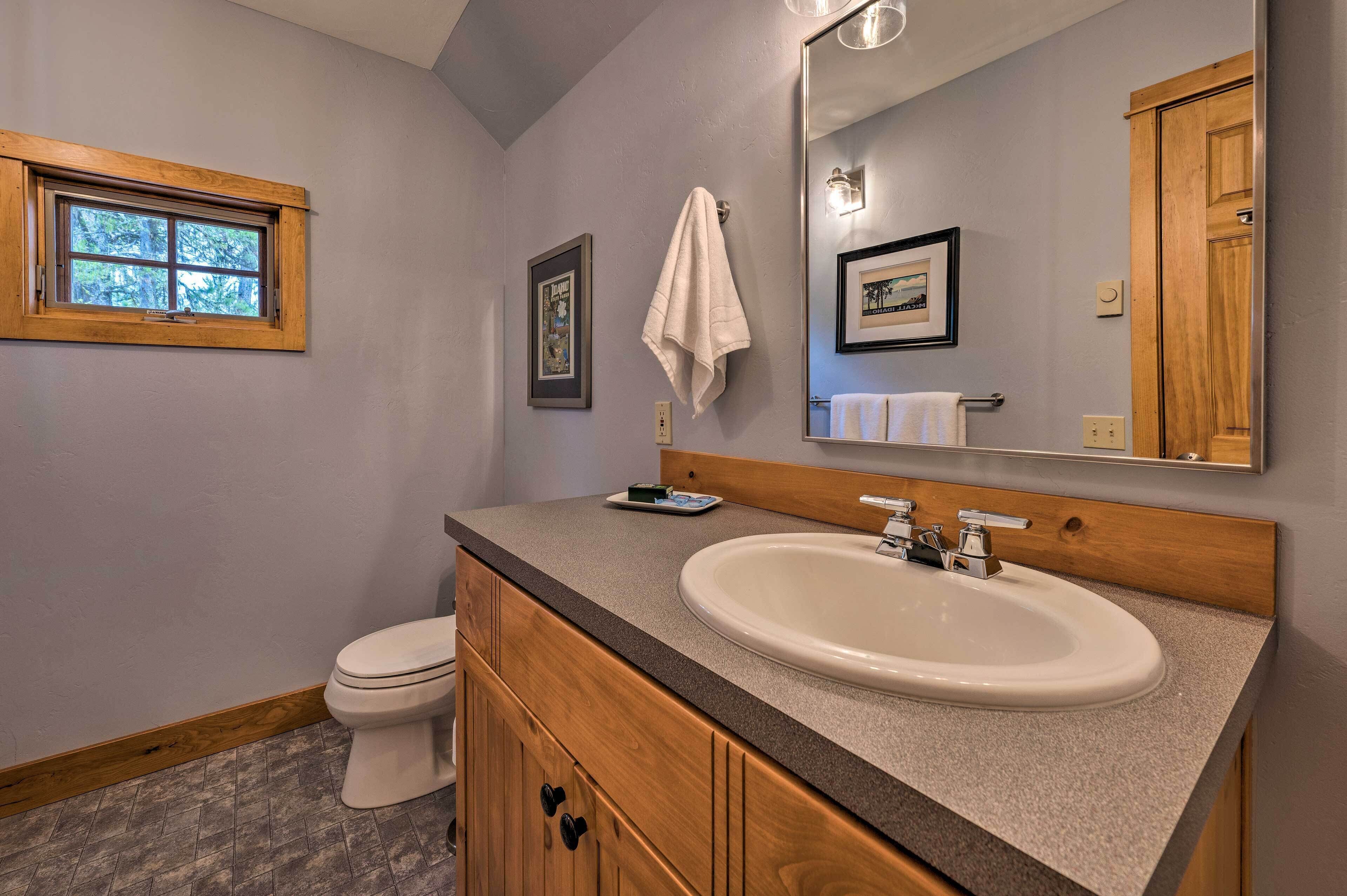 Une salle de bain avec un meuble-lavabo en bois, un lavabo blanc, un miroir et une fenêtre.