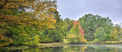 A wooden dock extending into a calm lake surrounded by autumn foliage.