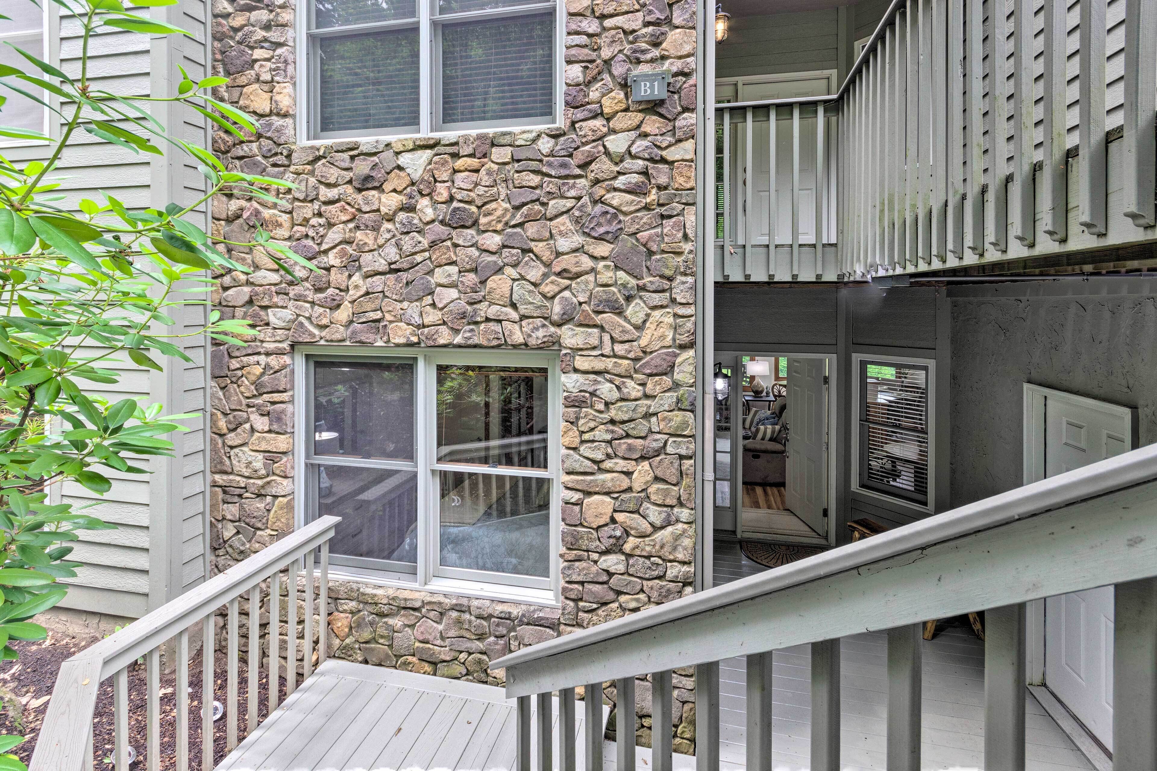 A two-story building with a stone facade, multiple windows, and a wooden deck.