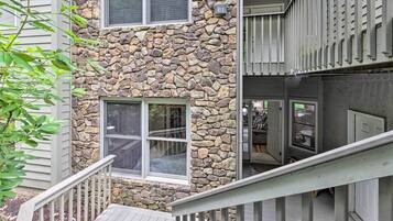 A two-story building with a stone facade, multiple windows, and a wooden deck.