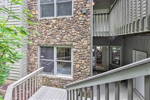 A two-story building with a stone facade, multiple windows, and a wooden deck. - Blue Ridge Mtn Views: Condo w/ Furnished Balcony (Burnsville)