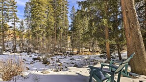 A bench in a snowy forest with trees and rocks. - Walk to Grand Lake: Riverfront Gem w/ Fireplace! (Grand Lake)