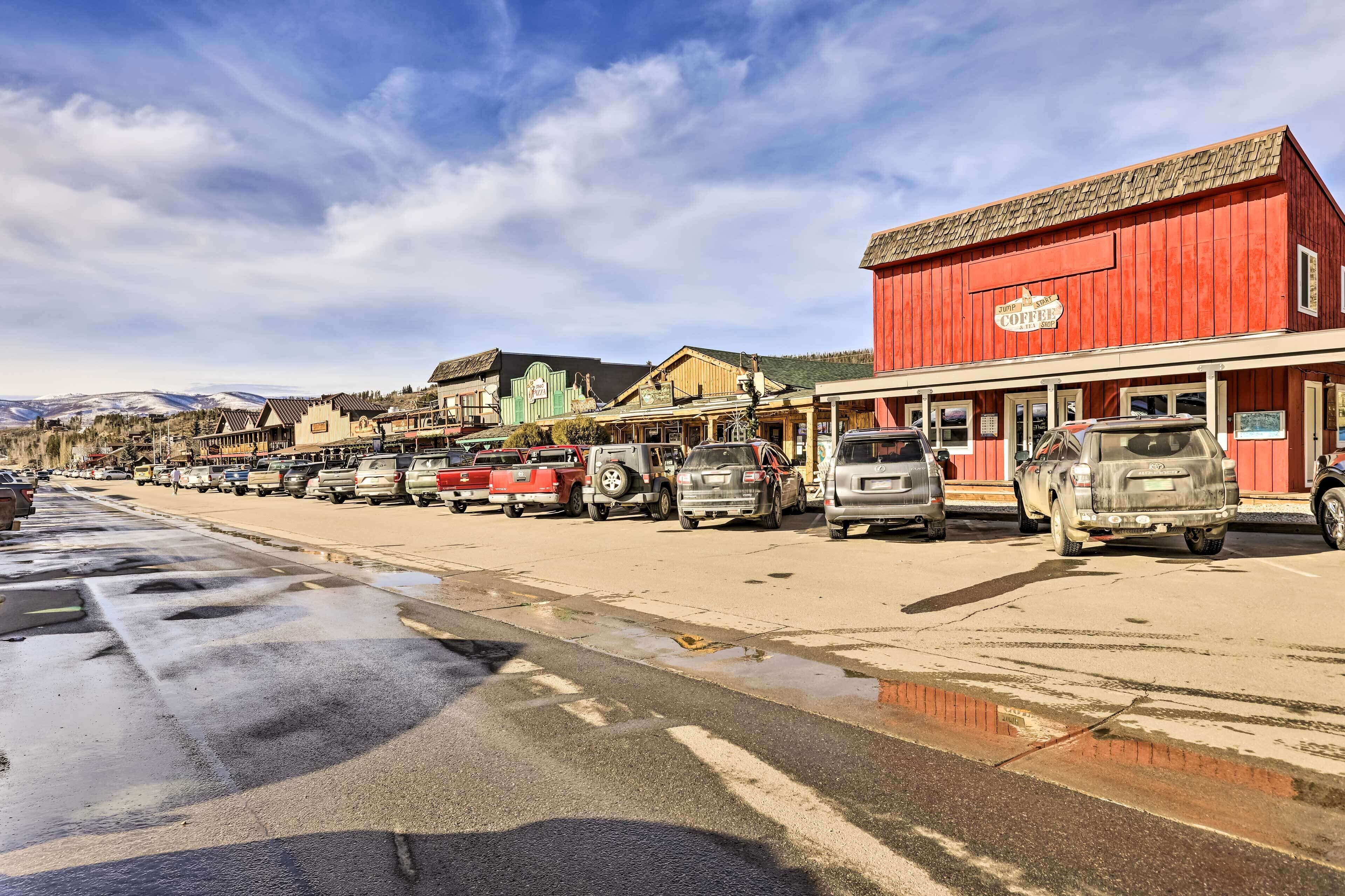 A row of parked cars along a street with buildings in the background.