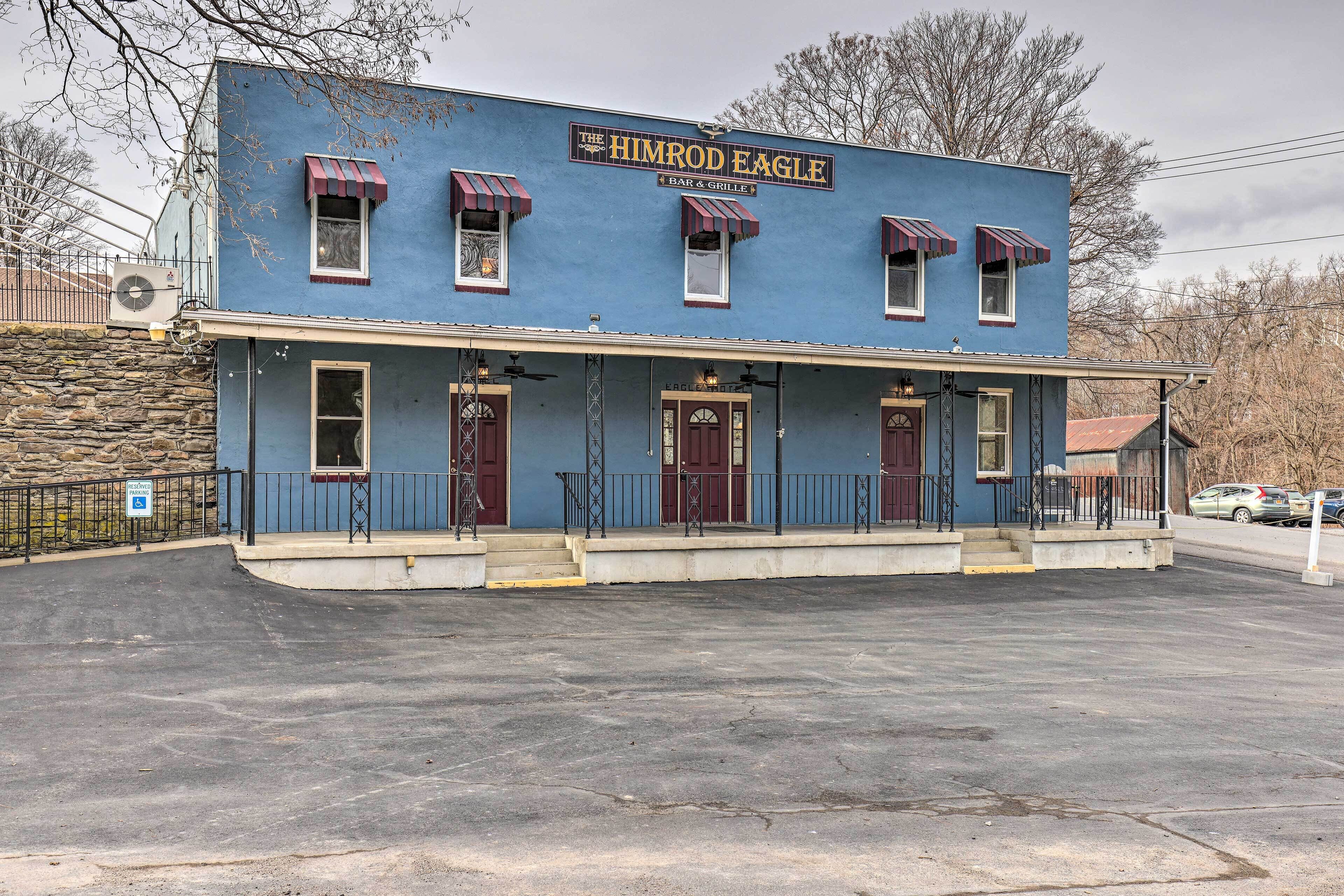 A two-story building with a blue facade and a sign reading "The Himrod Eagle 4 Bar & Grille".